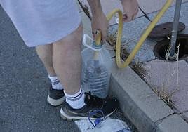 Un hombre rellenando una garrafa de auga.