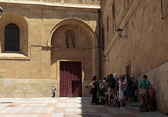 Varias personas se protegen del sol a la sombra de la Catedral.