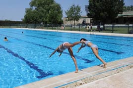 Dos jóvenes se lanzan a la piscina en las instalaciones del complejo deportivo del Helmántico.