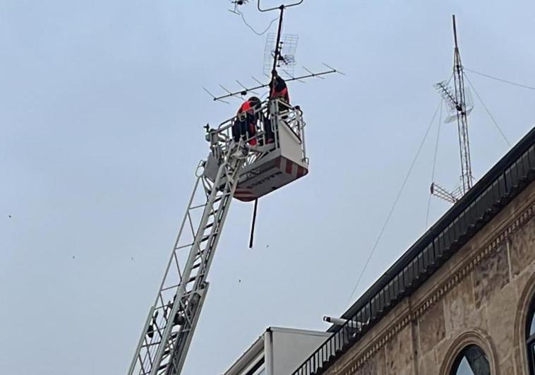 Los bomberos retiran una antena en un edificio del centro de al ciudad.