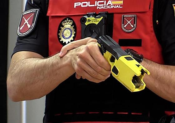 Un agente muestra una de las pistolas y la cámara del pecho.