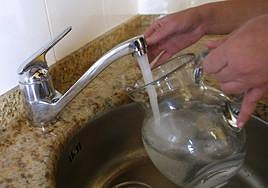 Una persona recoge agua en una jarra.