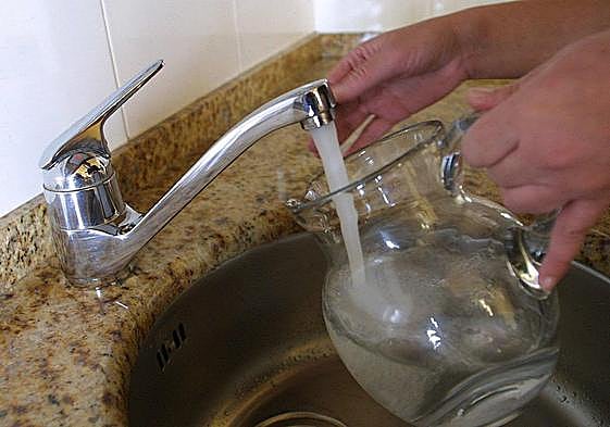 Una persona recoge agua en una jarra.