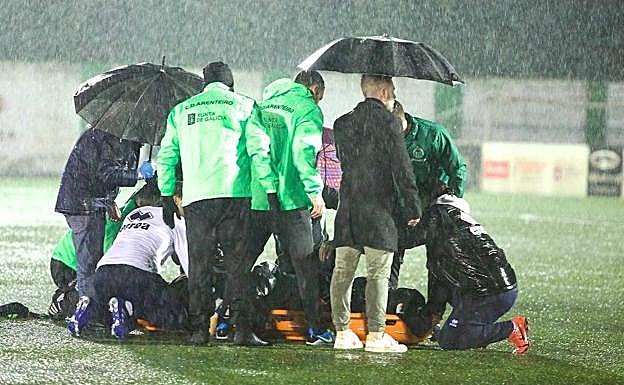 Los médicos atienden a Pol Bueso en el suelo durante la intensa lluvia caída ayer en el municipal. 