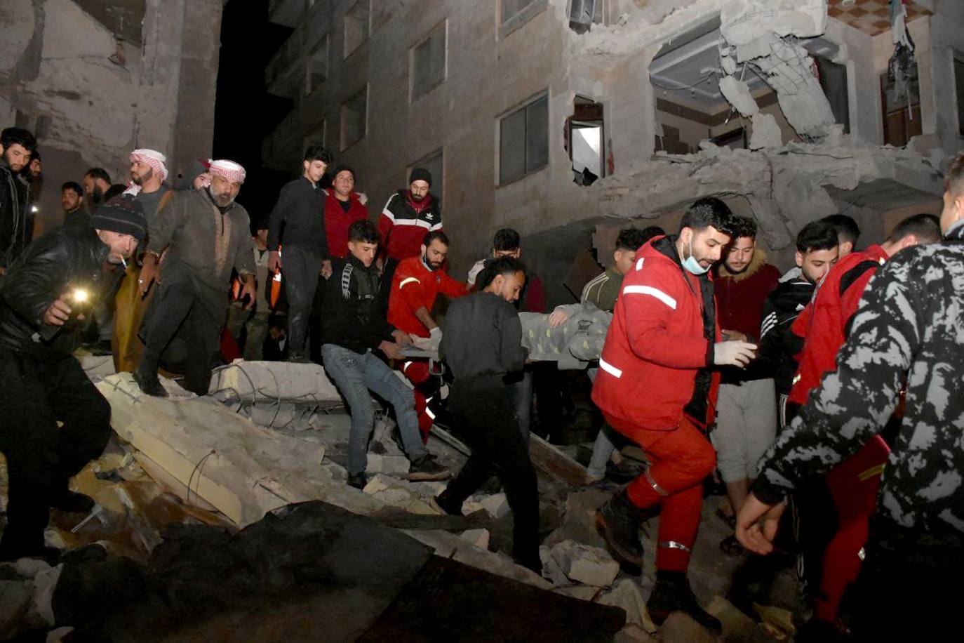 Un grupo de voluntarios ayuds a los servicios de emergencia a evacuar a víctimas entre los escombros de un edificio en Hama, al noroeste de Siria.