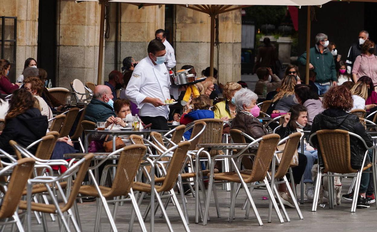 Un camarero sirve una mesa en la Plaza Mayor. 