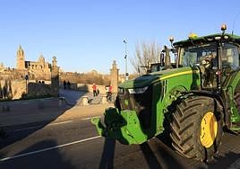 Un tractor este martes a su paso por el puente romano de Salamanca con las catedrales al fondo.