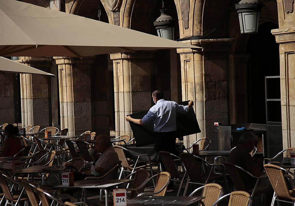 Un camarero dobla manteles en una terraza de la Plaza Mayor.