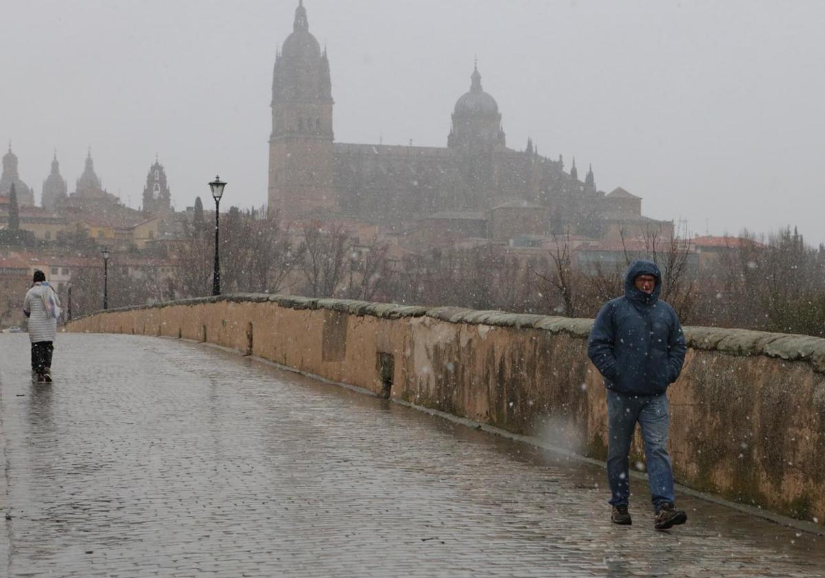 Varios ciudadanos pasean por el Puente Romano el pasado sábado durante la nevada.