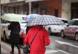 Una mujer se refugia de la nieve bajo un paraguas.