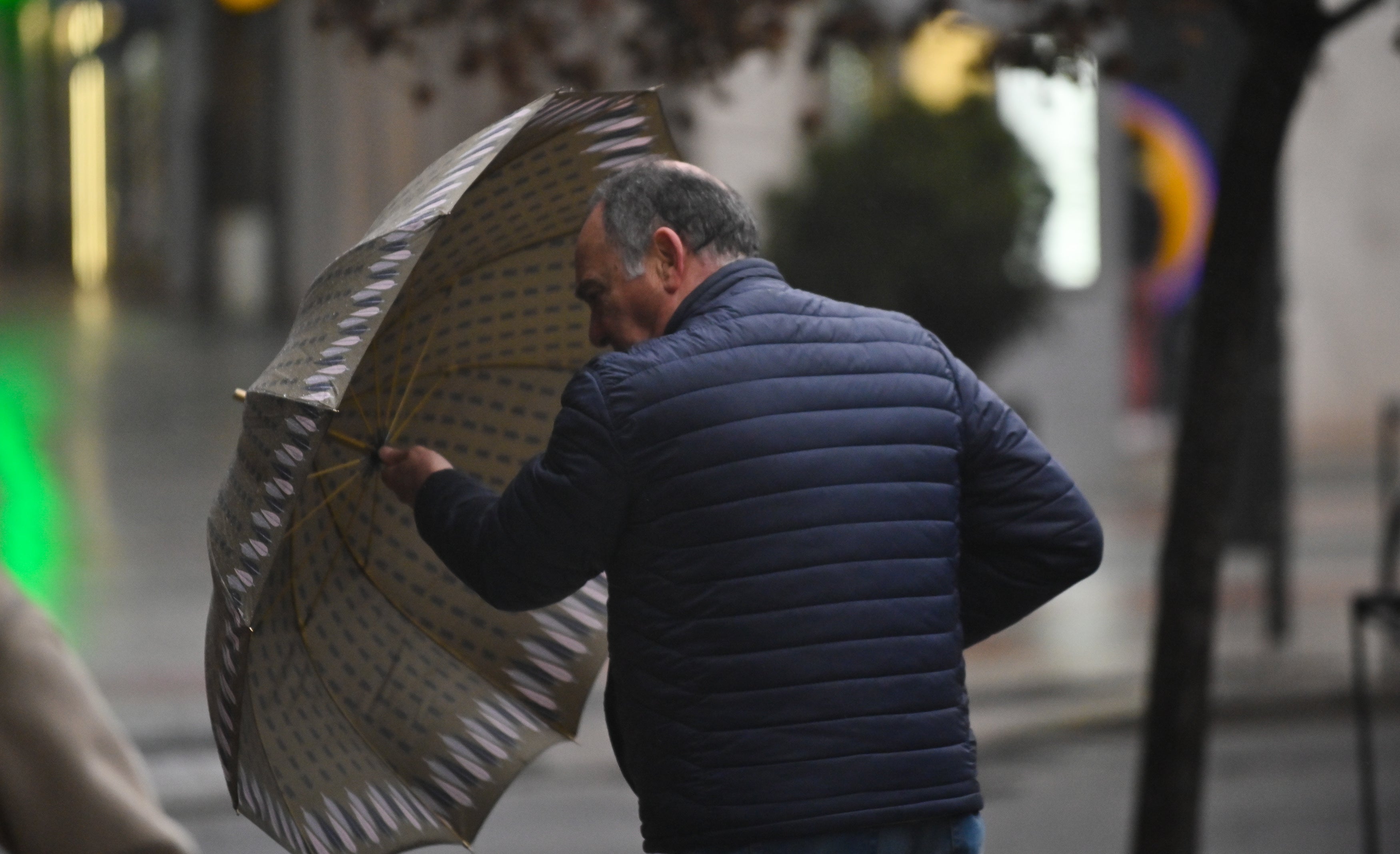 Un hombre trata de protegerse del viento.