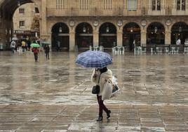 Mujer en la Plaza Mayor protegiéndose de la lluvia