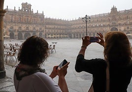 Dos personas hacen fotos en la Plaza Mayor de Salamanca durante una tormenta.
