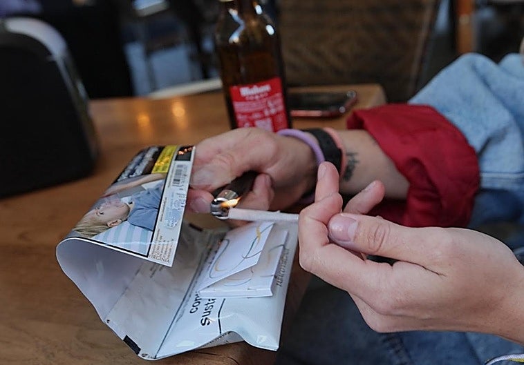 Una chica se enciende un cigarro en la terraza de un bar de Salamanca.