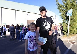 Un padre y su hija posan con varias entradas delante de la gran cola de aficionados que esperaban para comprar entradas para la final entre Avenida y el Valencia Basket.