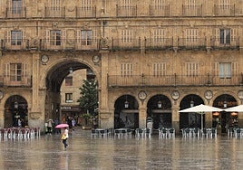 Viandantes caminan bajo la lluvia en la Plaza Mayor