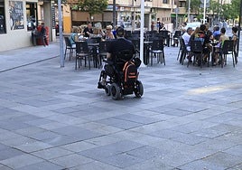 Una persona con movilidad reducida se acerca a una terraza.
