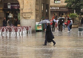 Un viandante atraviesa la Plaza Mayor bajo la lluvia.