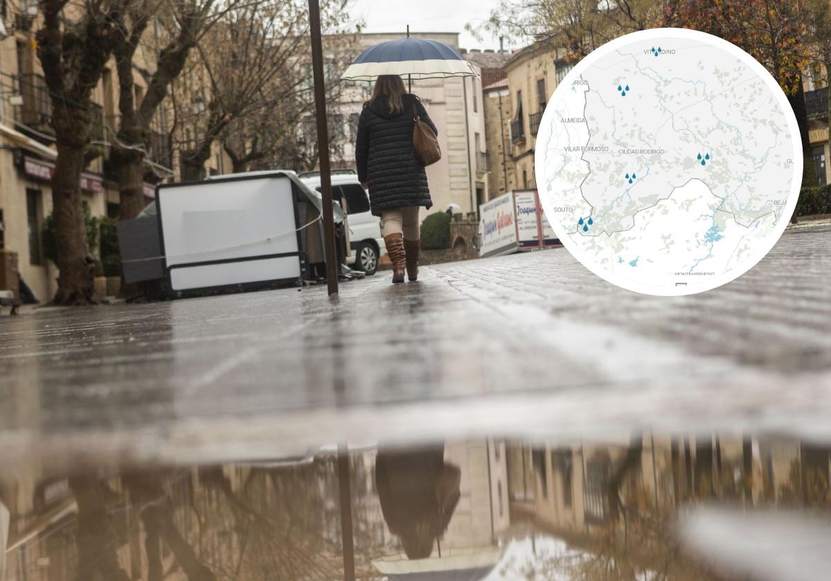 Una mujer camina con su paraguas abierto con su imagen reflejada en un charco.