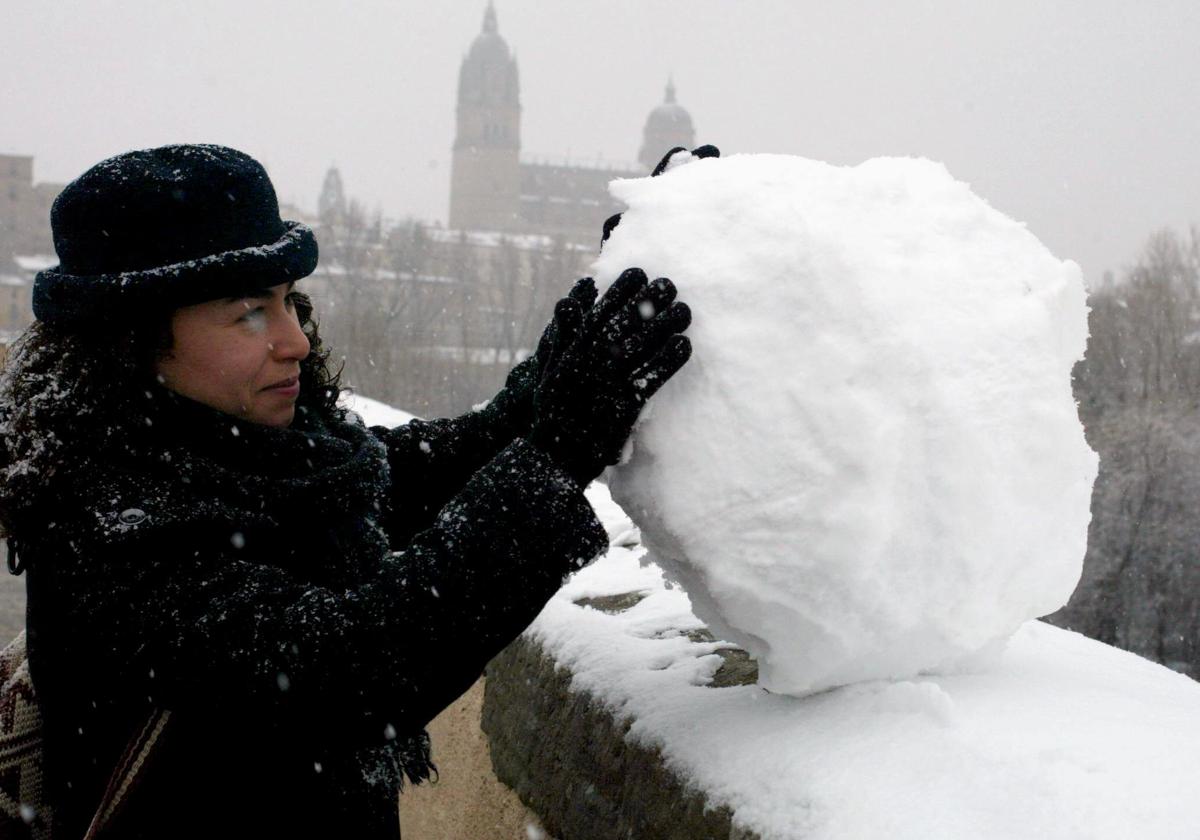 Una mujer hace una bola de nieve en las calles de Salamanca en una imagen de archivo.