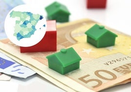 Varias casas del juego del 'Monopoly' encima de billetes de euros y, a la izquierda, el mapa de España con los datos de todas las provincias.