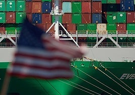 La bandera de Estados Unidos delante de un gran barco que transporta mercancías.