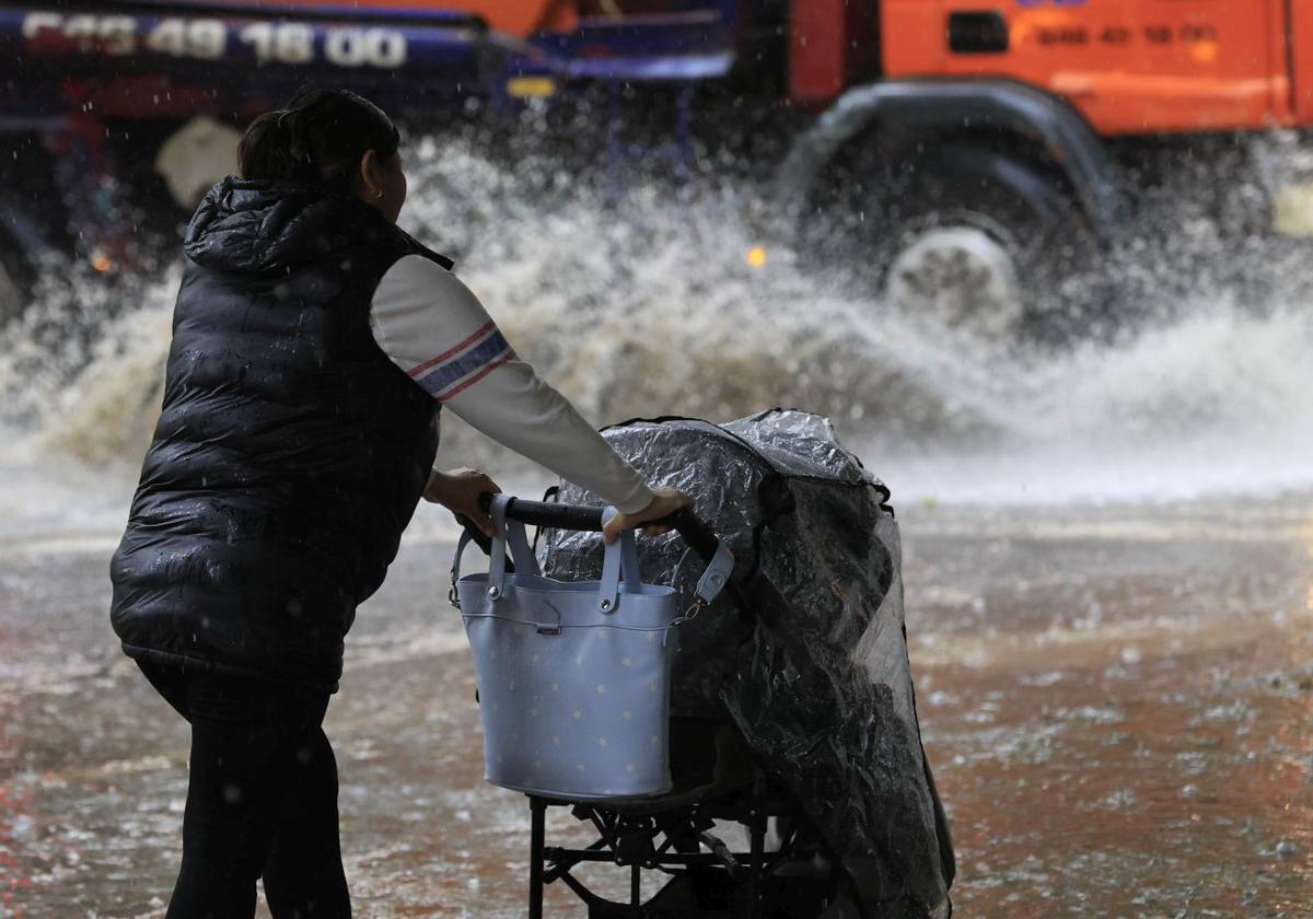 Una mujer con un carrito de bebé en plena tormenta.