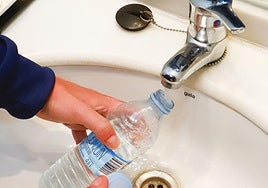 Una persona recoge agua del grifo en una botella.
