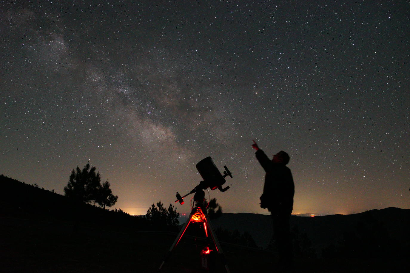 Un hombre junto a un telescopio señalando la Vía Lactea en el observatorio astronómico 'El Cielo de Salamanca'.