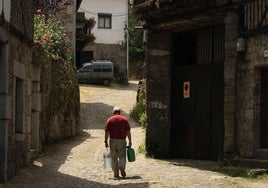 Un hombre lleva garrafas de agua en un pueblo de Salamanca.