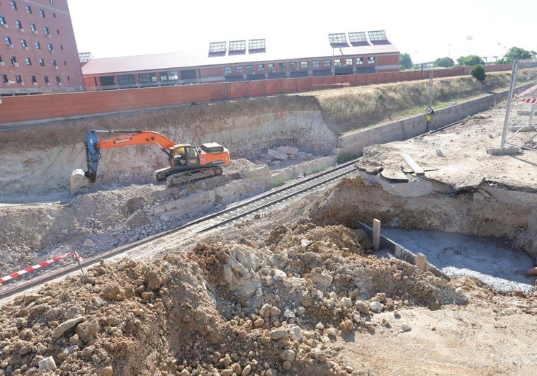 Una excavadora mueve la tierra tras la demolición del puente.