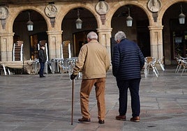 Dos personas mayores pasean por la Plaza Mayor de Salamanca.