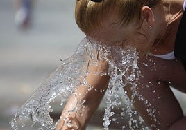 Una mujer se refresca en una fuente.