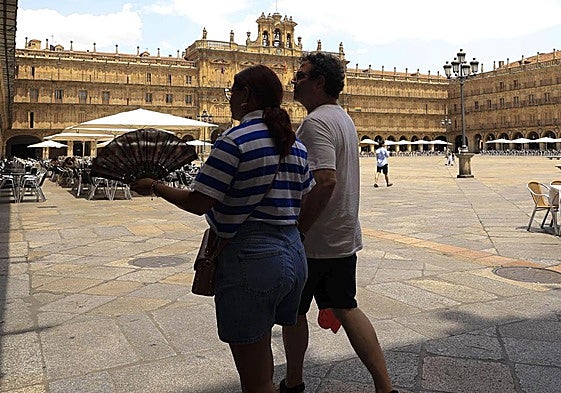 Varias personas pasean por la Plaza Mayor de Salamanca durante un soleado día.