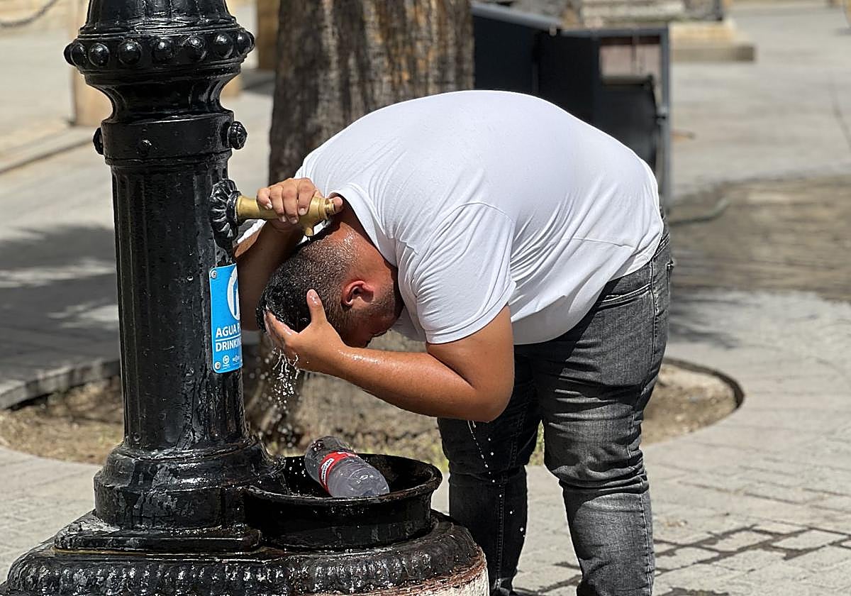 Un hombre se refresca en una fuente.