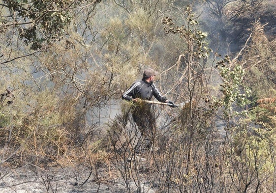 Un hombre ayuda a sofocar las llamas en el incendio de La Alberca.