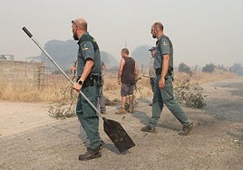 Dos guardia civiles ayudan a los vecinos en el incendio de Cipérez este viernes.