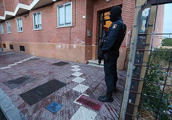 Un agente de la Policía Nacional armado frente a un portal.