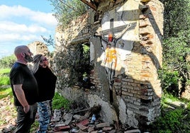Zwei Personen betrachten das zerstörte Werk.