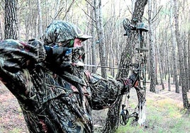 Ein Jäger in Tarnkleidung bei der Vorbereitung zum Abschuss eines Pfeils.