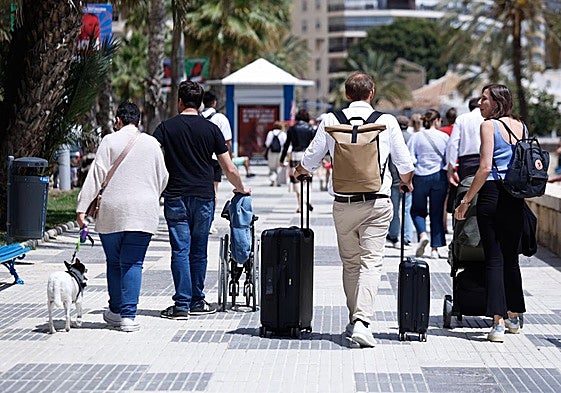 Ein Tourist schleppt seine Koffer über die Strandpromenade der Hauptstadt der Costa del Sol.