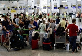 Touristen stehen am Check-in-Schalter des Flughafens Malaga Schlange.
