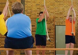 Übergewichtiger Junge sitzt während des Sportunterrichts auf der Bank.