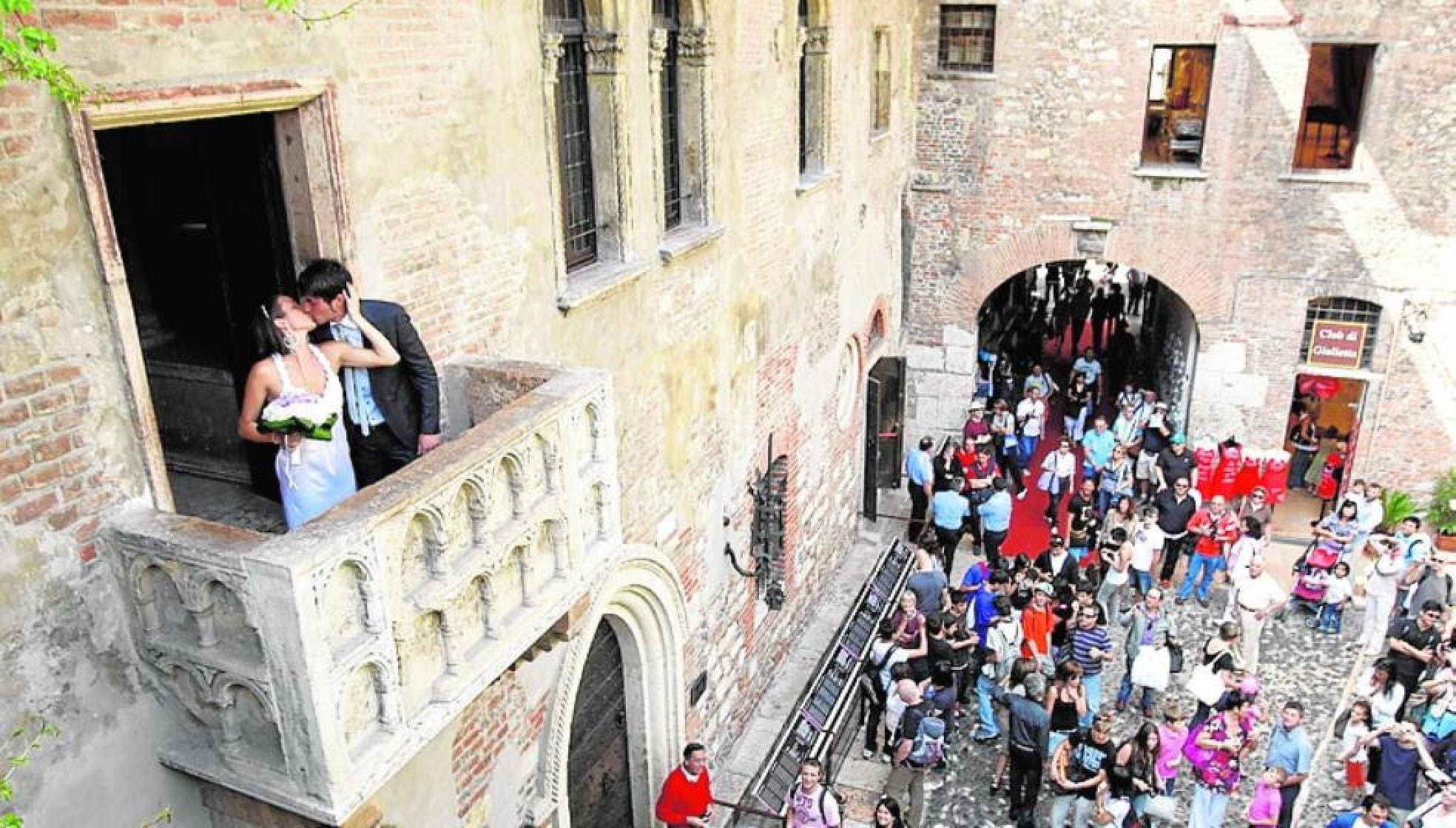 Newlyweds embrace on Juliet's balcony. 