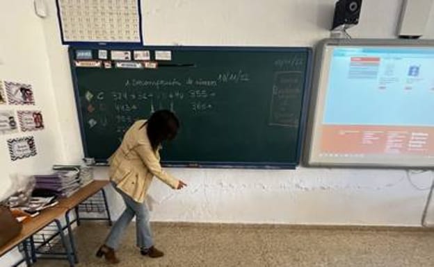 Imagen principal - Head teacher Mari Ángeles Pérez points to cracks in the walls and plaster coming off in classrooms and corridors 