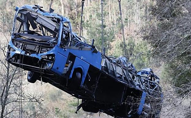 The wreckage of the bus is lifted from the scene of the accident.
