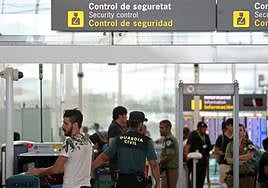 Passengers queue at an airport security control.