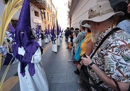 Tourists watch a procession in Malaga city centre.