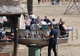 The skewered fish are cooked over hot charcoals on the beach.