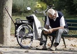 A pensioner reading a newspaper in a park.